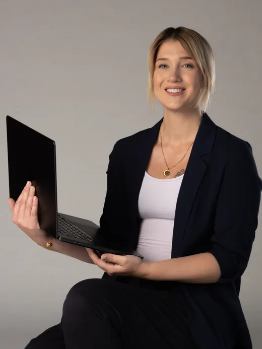 Monika sitzt mit einem Laptop und arbeitet